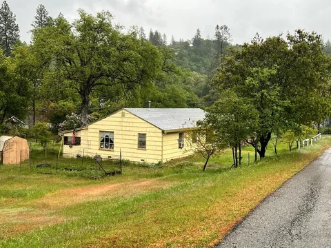 Yellow ranch house on a tree-lined rural lot